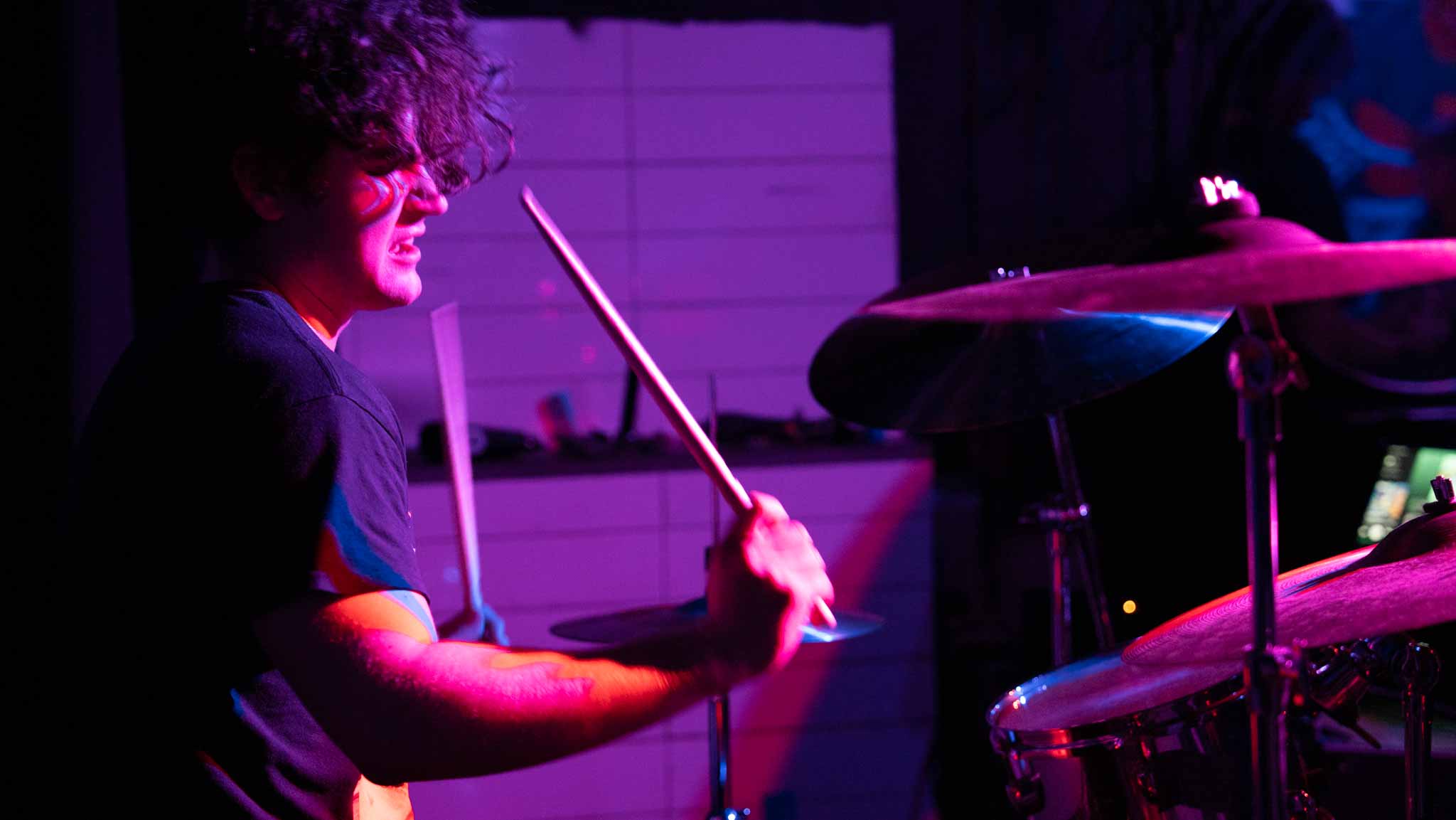 Drummer in profile with one drumstick raised